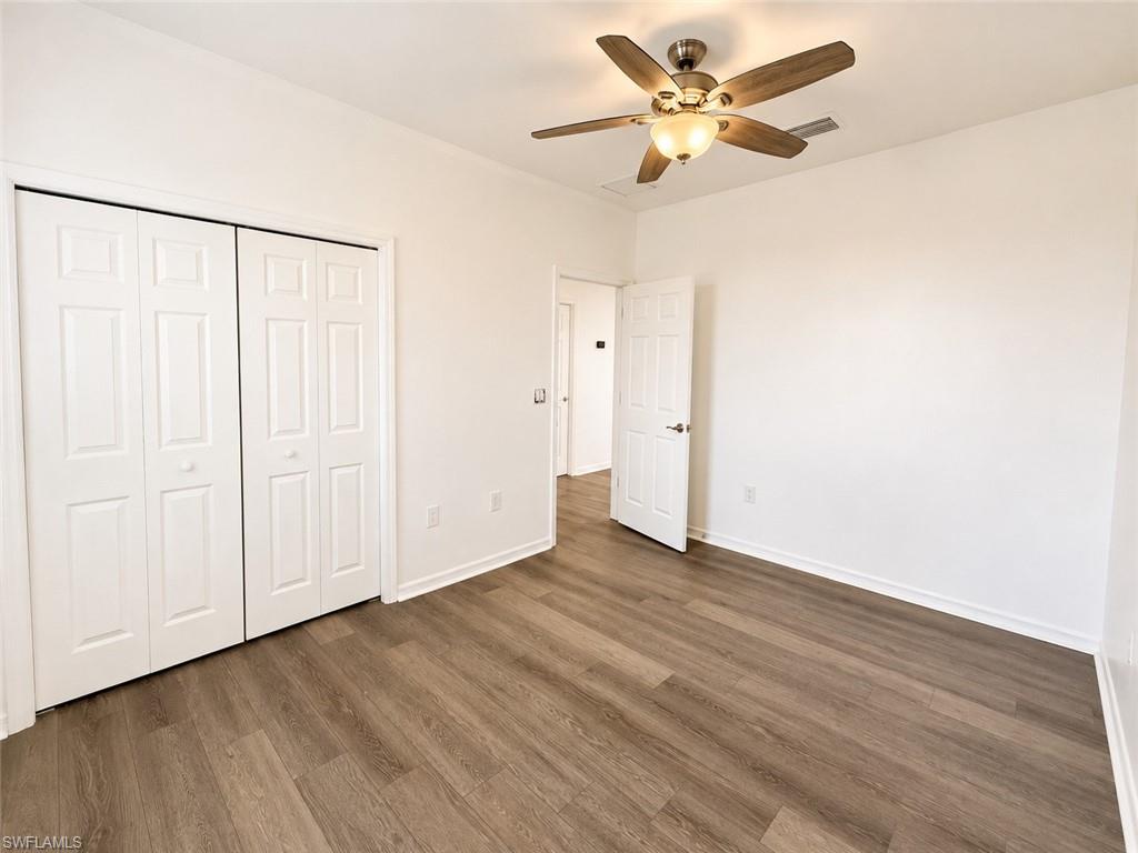 Wood-finish flooring, bright white walls, and a ceiling fan with integrated lighting