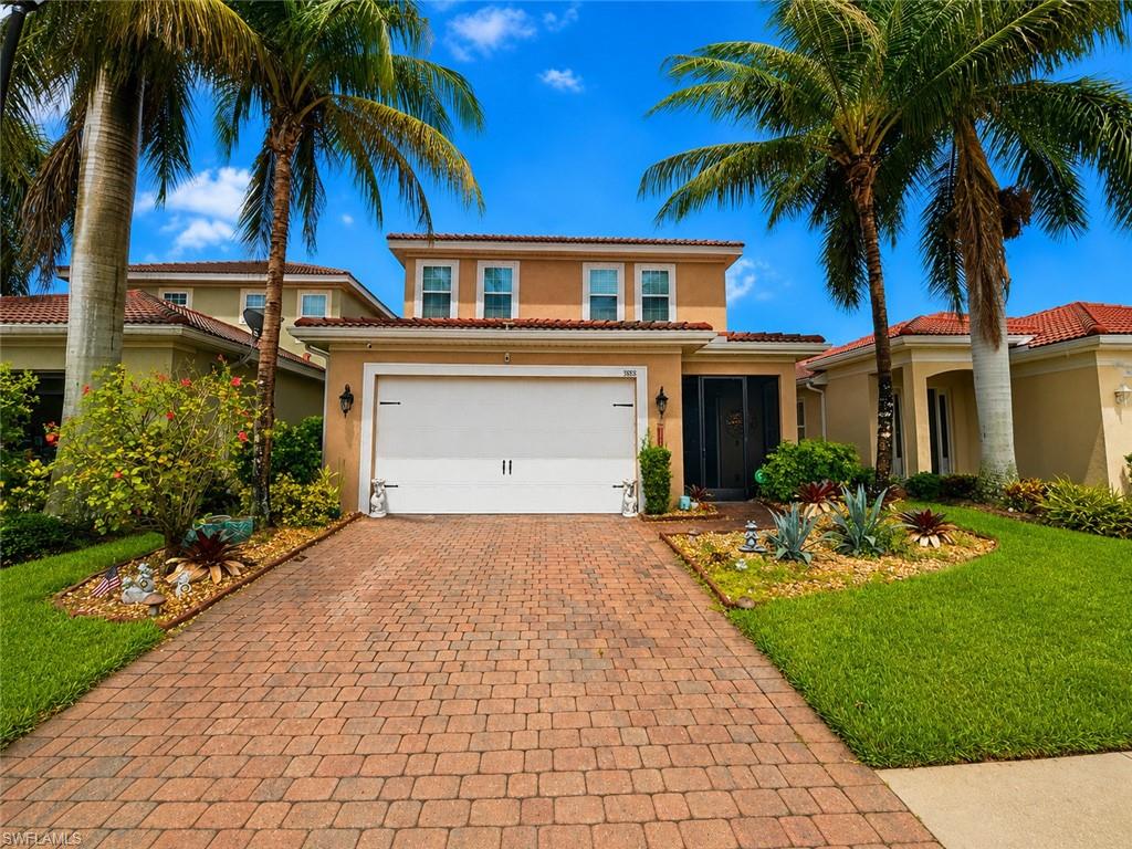 Stucco exterior with a tile roof, paver driveway, and a two-car garage
