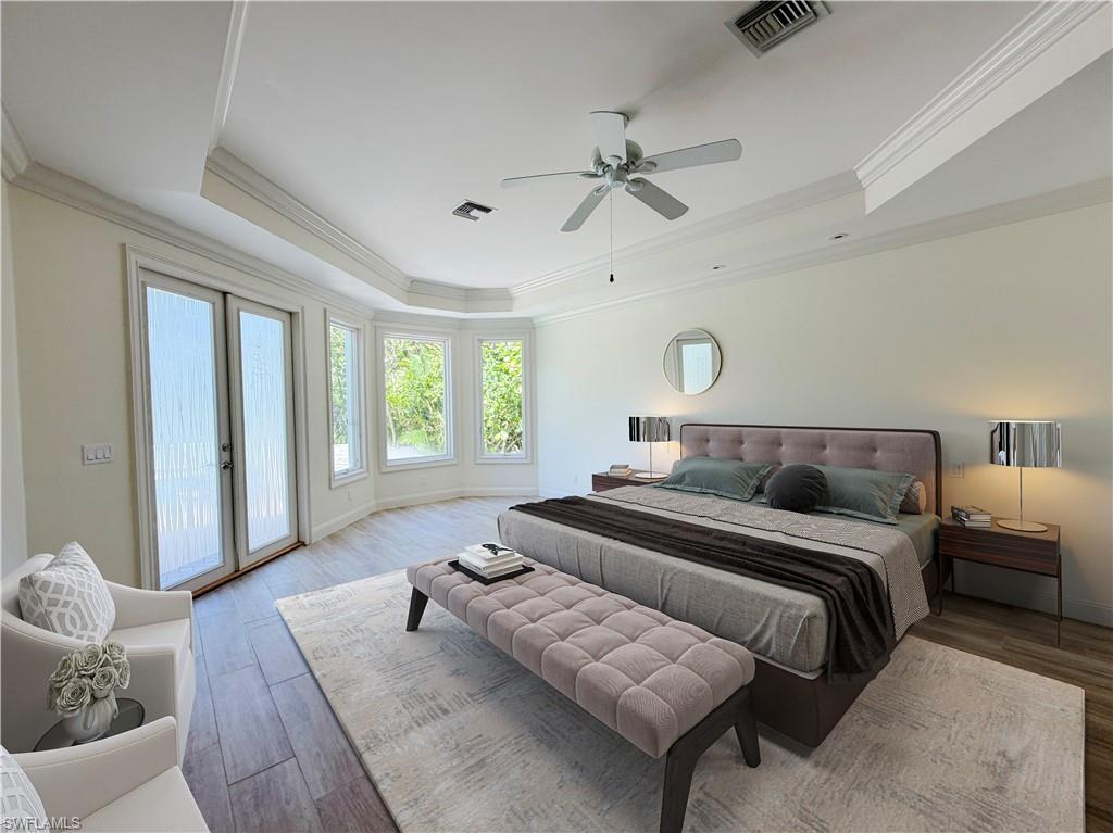 Wood-finish flooring, bay window, tray ceiling with crown molding, and double glass doors