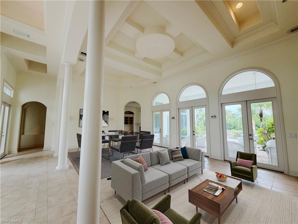 Tiled flooring, coffered ceilings, arched doorways, interior columns, and multiple sets of French doors with arched transoms