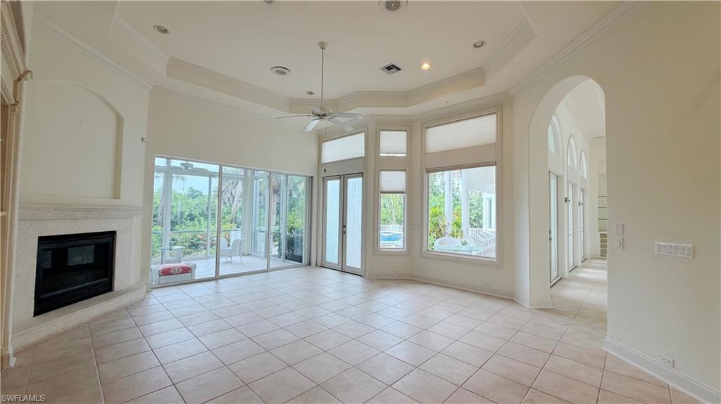 Spacious living area featuring a stone-clad fireplace, large format tile flooring, and a tray ceiling with recessed lighting