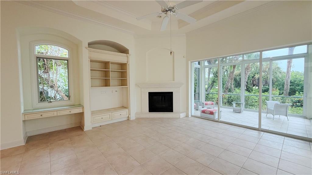 Spacious interior with neutral-toned tile flooring, a fireplace, and a built-in shelving unit with desk