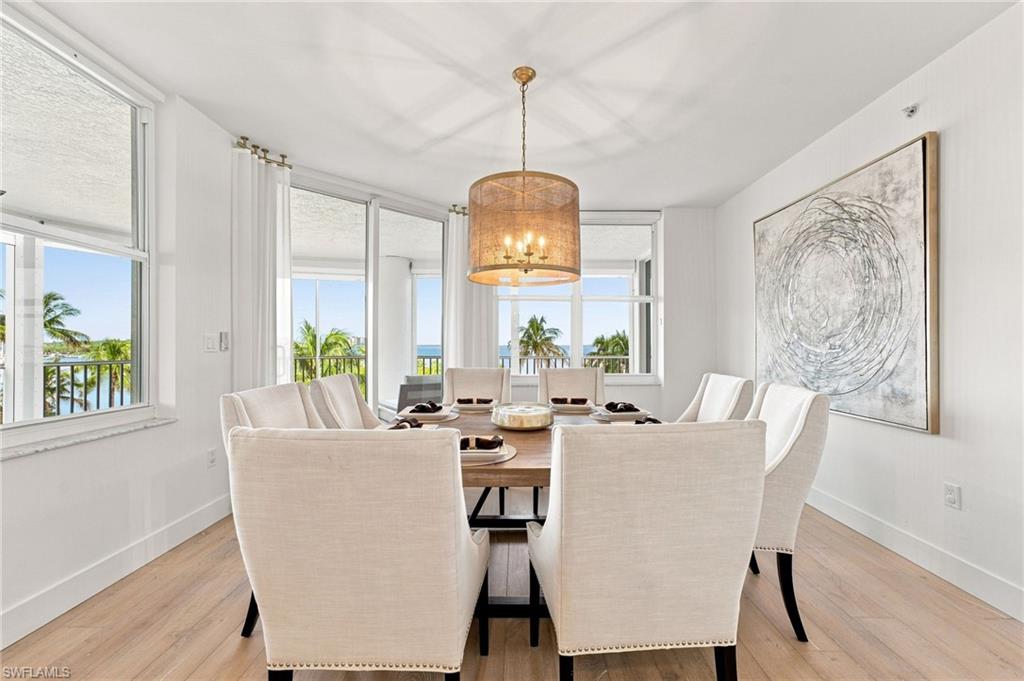 Light wood-finish flooring, a contemporary chandelier, large windows, and a glass sliding door
