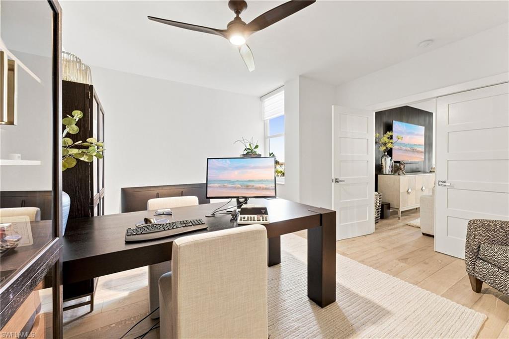 Light wood-finish flooring, white walls, and a ceiling fan with integrated lighting