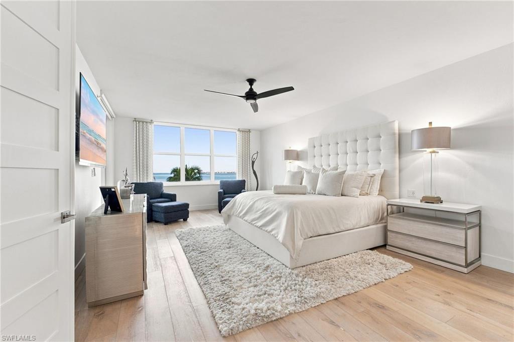 Expansive window offering water scenery, neutral wood-finish flooring, recessed lighting, and a contemporary ceiling fan