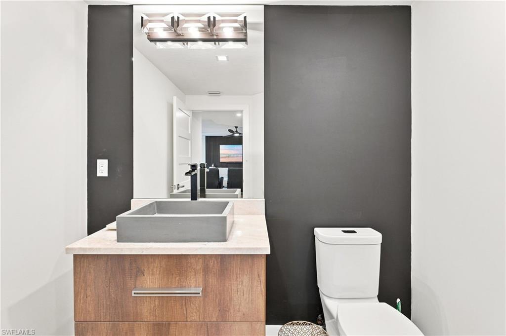 Wood-finish vanity with a light-toned countertop, rectangular vessel sink, and wall-mounted faucet