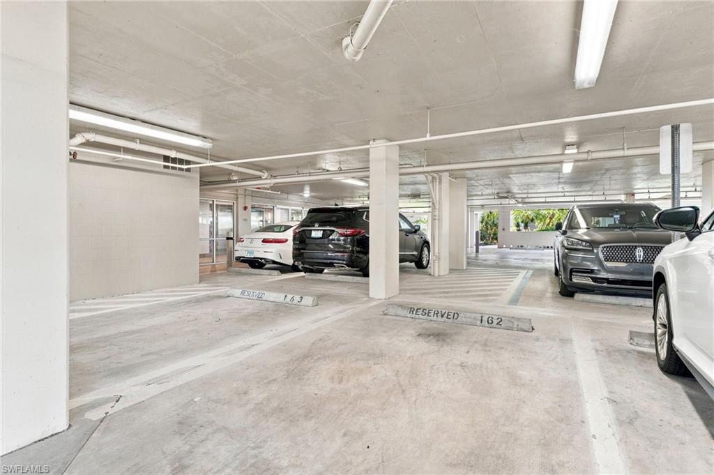 Underground parking garage featuring concrete flooring, overhead fluorescent lighting, and designated parking spaces
