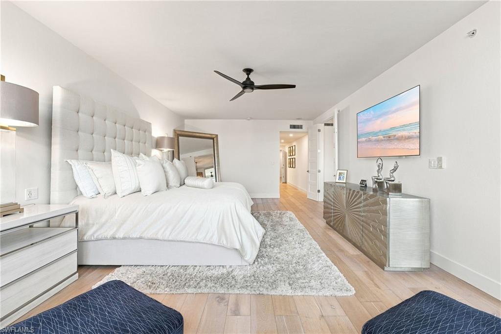 Light wood-finish flooring, white walls, and a black ceiling fan
