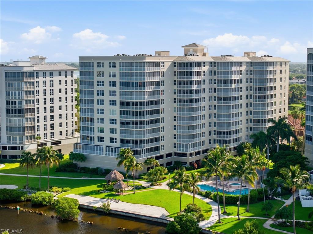 Contemporary multi-story building featuring expansive balconies, an outdoor swimming pool, and tropical landscaping