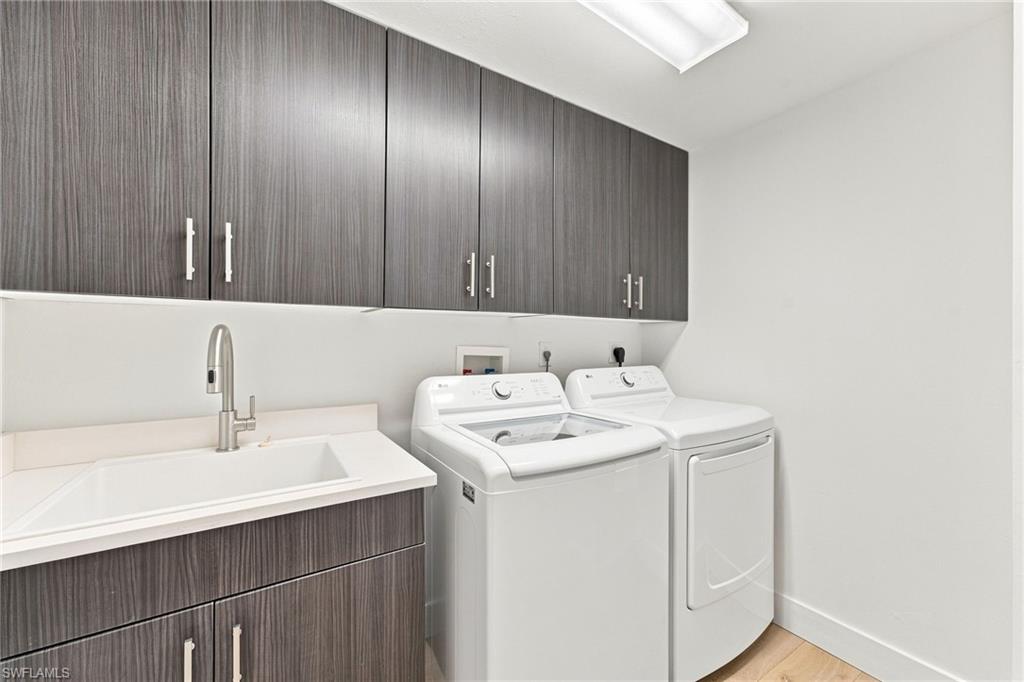Upper and lower wood-finish cabinetry, integrated sink with a gooseneck faucet, light countertop, and light wood-finish flooring