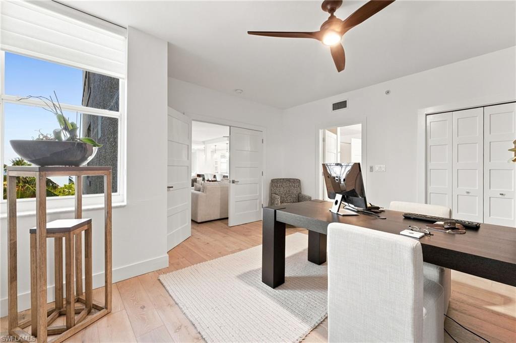 Light wood-finish flooring, white walls, and a modern ceiling fan with integrated lighting