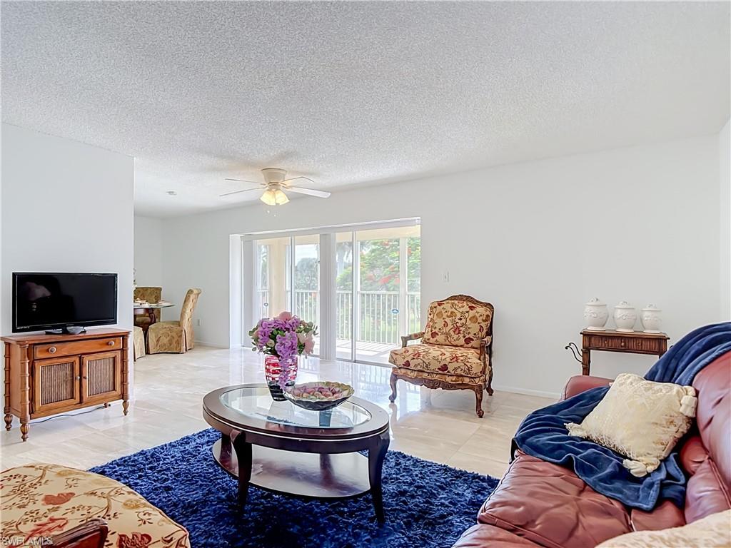 Living area featuring light-toned tile flooring throughout, white walls, and a ceiling fan