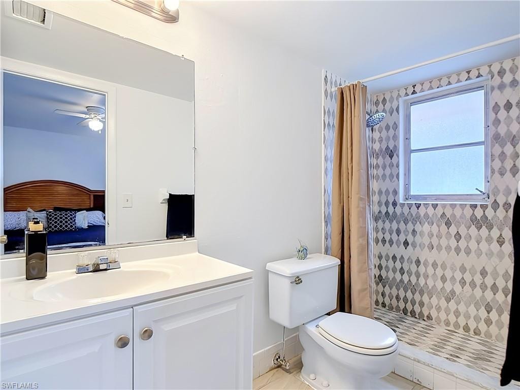 Bathroom featuring a white vanity with integrated sink, a wall-mounted mirror, and a shower area with patterned tile walls