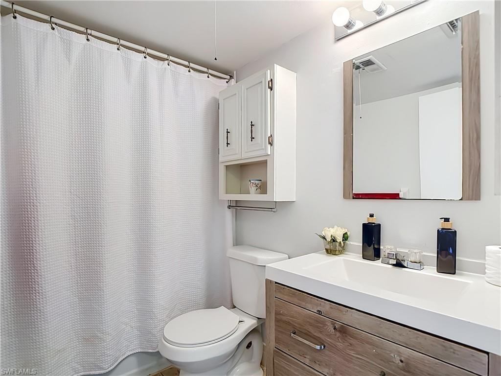 Bathroom featuring a wood-finish vanity with an integrated white sink and chrome faucet