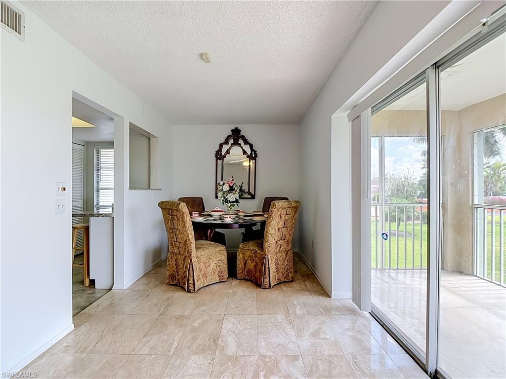 Tiled flooring extends through this dining area, featuring a decorative wall mirror and a pass-through opening to an additional room