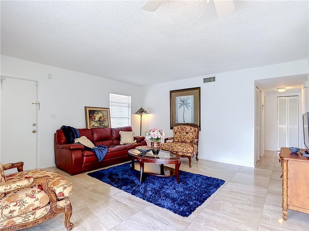 Spacious living area featuring light-toned tile flooring throughout and white walls