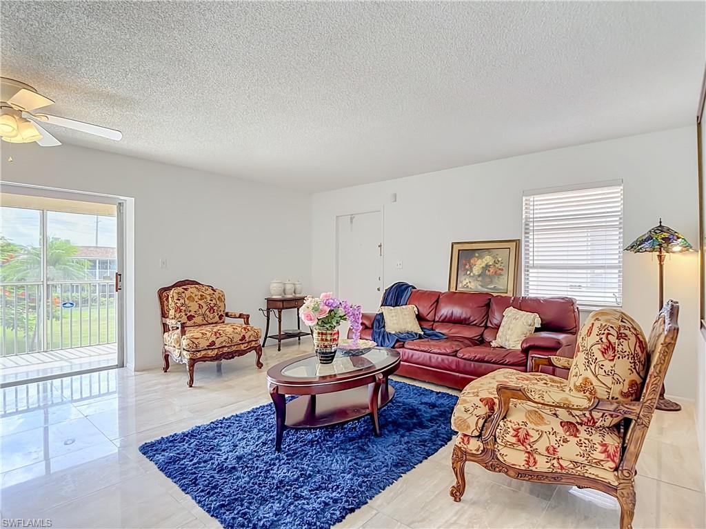 Spacious living area featuring polished tile flooring, white walls, and a ceiling fan