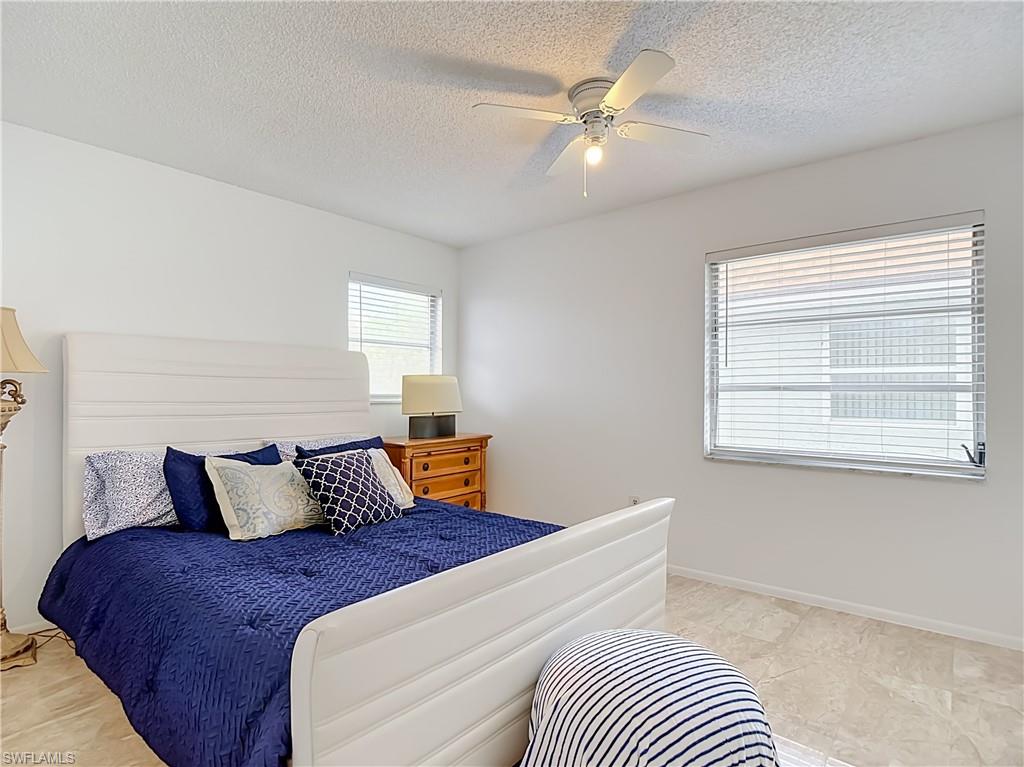 Neutral white wall paint, two windows with horizontal blinds, a ceiling fan with light fixture, and tile flooring