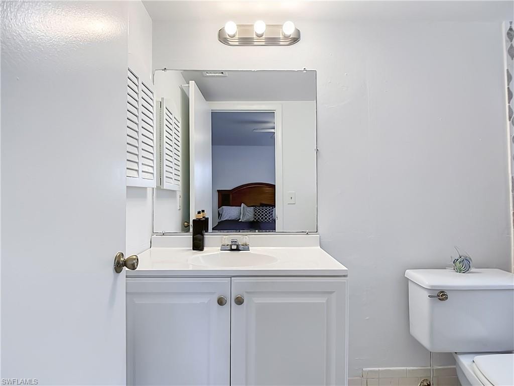 Bathroom vanity featuring white cabinetry with brushed nickel hardware, a white countertop, and a rectangular undermount sink