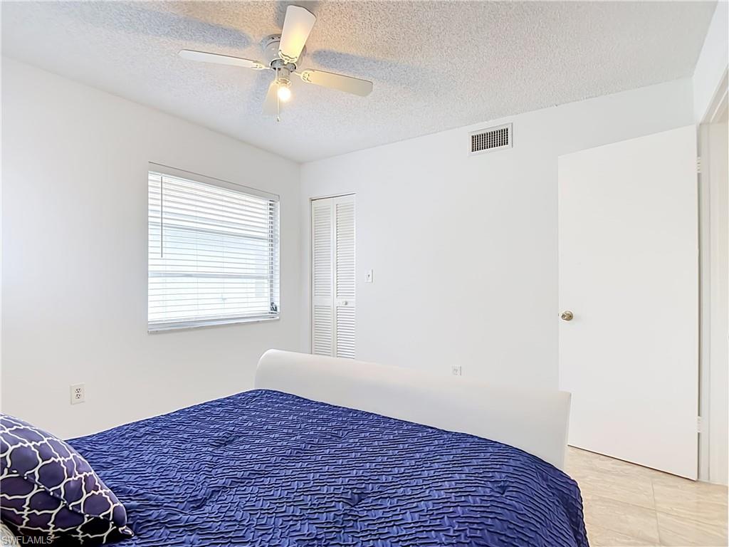 White-walled interior space featuring a window with horizontal blinds, a ceiling fan with light fixture, and tile flooring