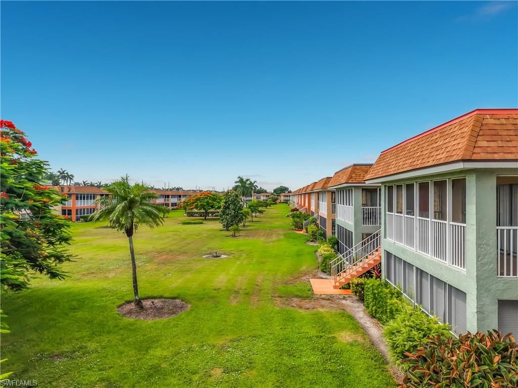 Row of multi-story buildings featuring screened balconies and patios, textured stucco exteriors, and orange shingle roofs