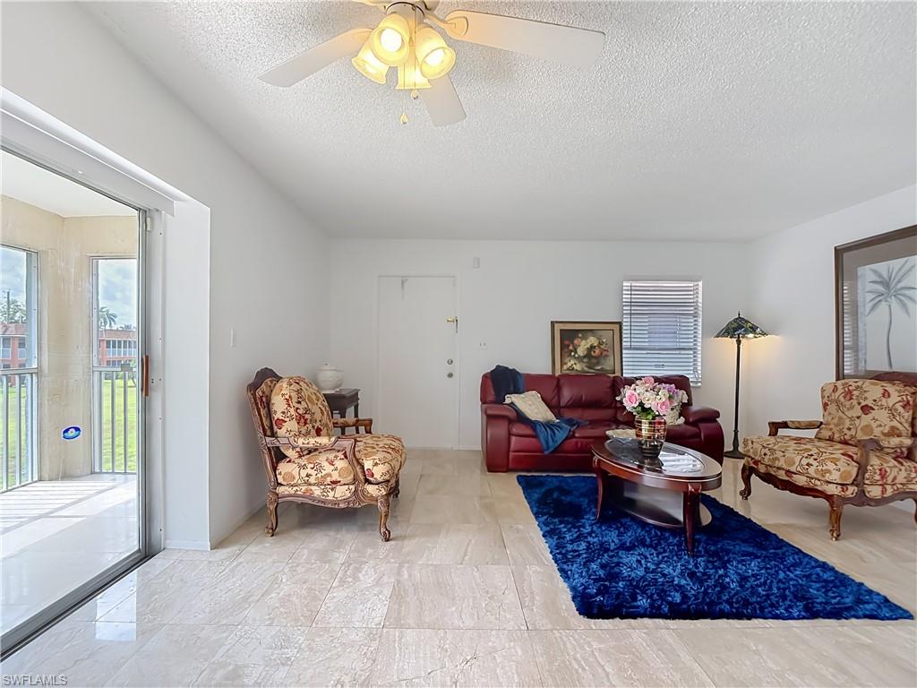 Living area featuring large format tile flooring, a ceiling fan, and sliding glass doors opening to an enclosed patio