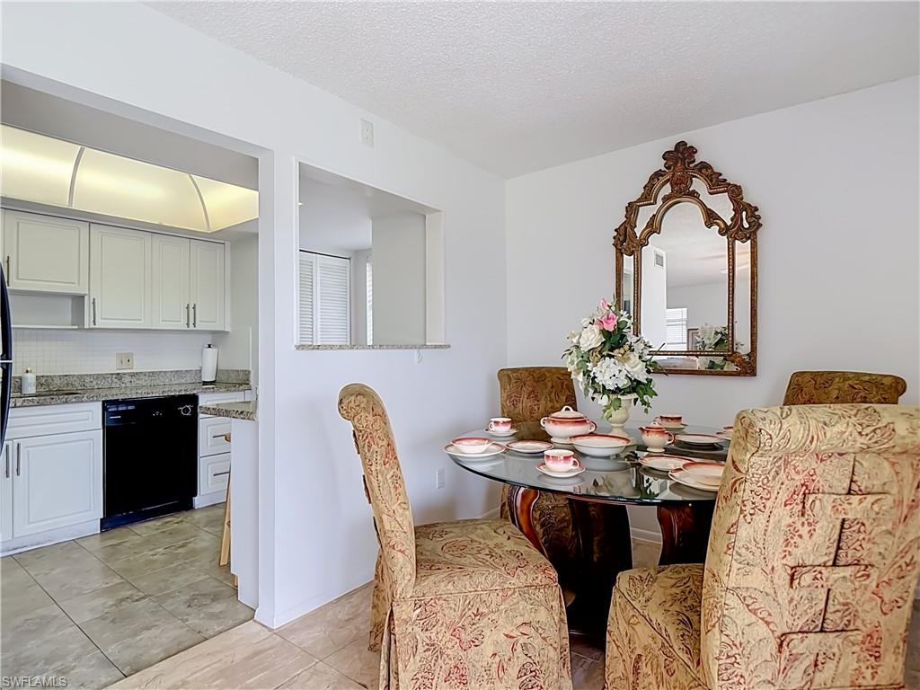 Dining area featuring a glass-top table, decorative wall mirror, and a pass-through window to the kitchen