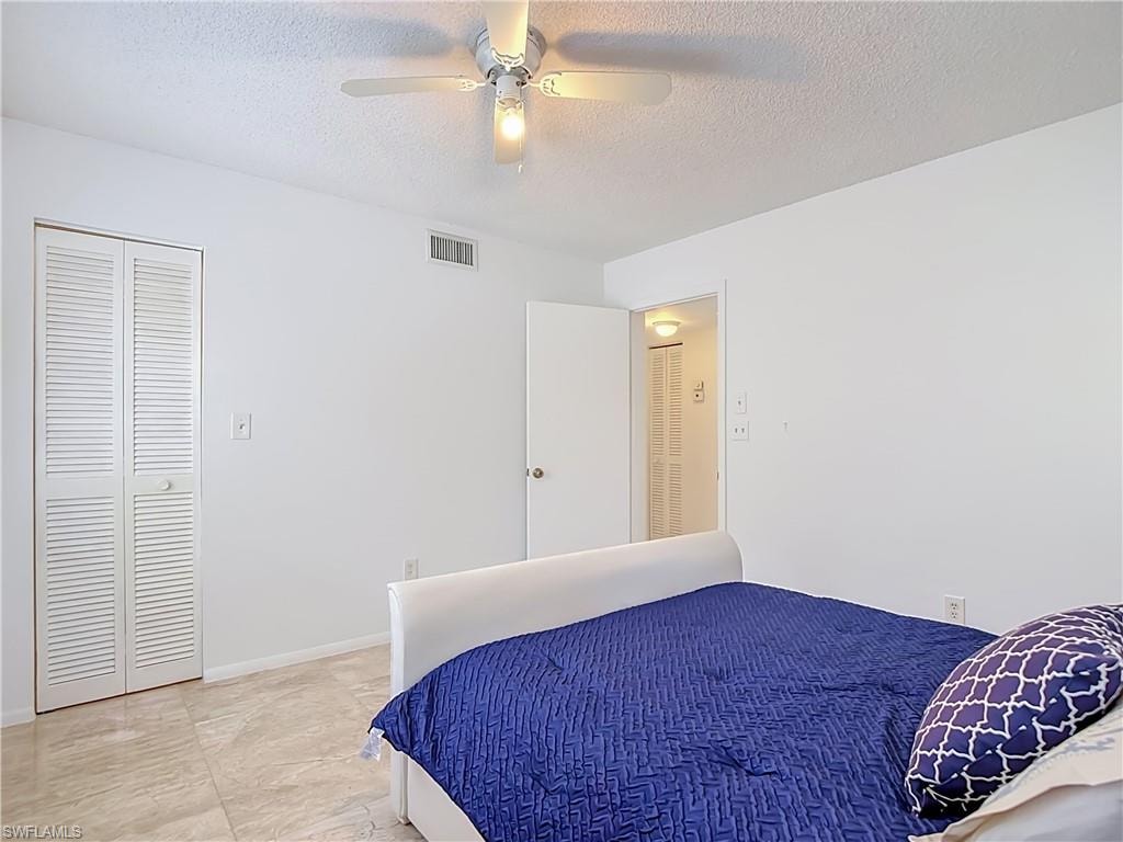White walls featuring a louvered bi-fold closet door, tile flooring, and a ceiling fan with integrated lighting