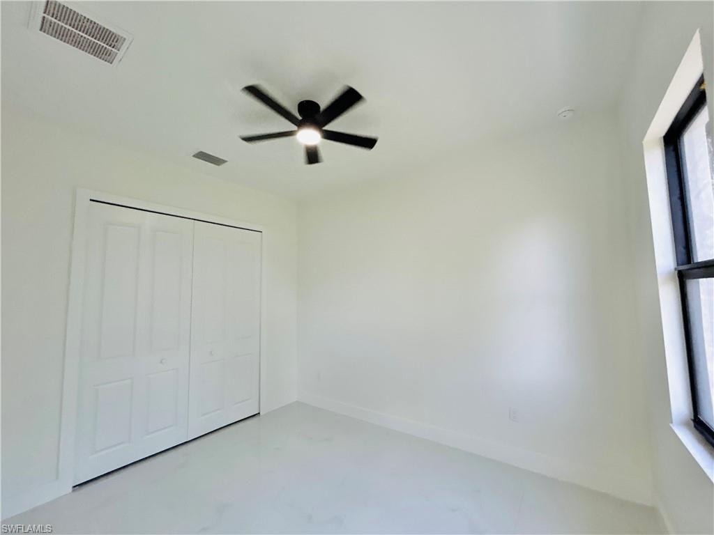 Integrated ceiling fan and light fixture, white bi-fold closet doors, white painted walls, and a large window with dark trim