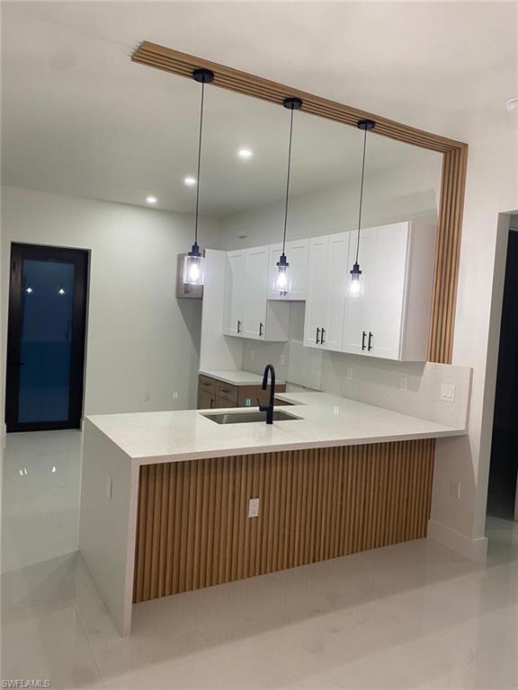 Kitchen featuring a central island with a waterfall countertop, integrated sink, and wood-slat paneling