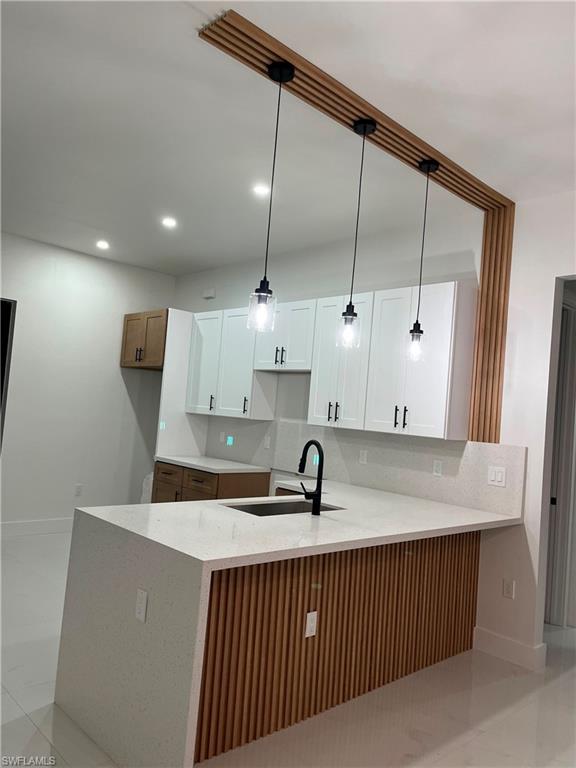 Kitchen featuring a waterfall island with stone countertops and wood slat detailing, recessed lighting, and a pendant light fixture