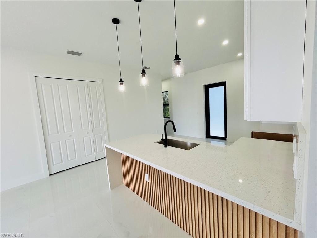 Kitchen island with a white speckled countertop, integrated sink, and matte black faucet. Aundry behind double doors.