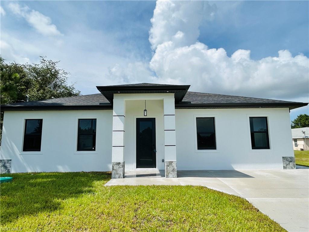 Contemporary exterior with a covered entry, dark shingle roof, and contrasting dark-framed windows
