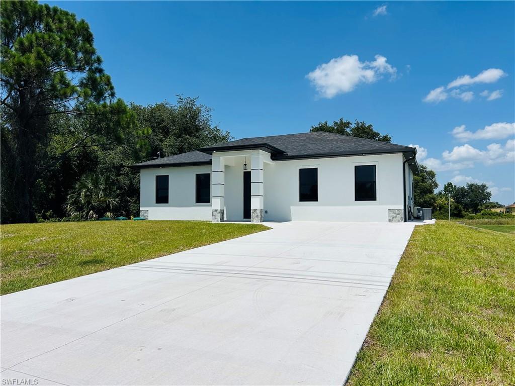 Contemporary exterior with a dark shingle roof, white stucco facade, and black-framed windows