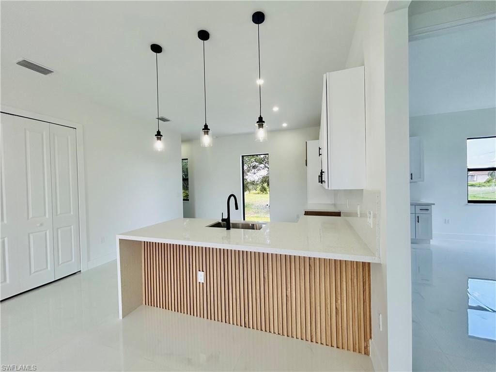 Modern kitchen island with a slatted wood-finish accent panel, quartz countertop, and black pendant lighting