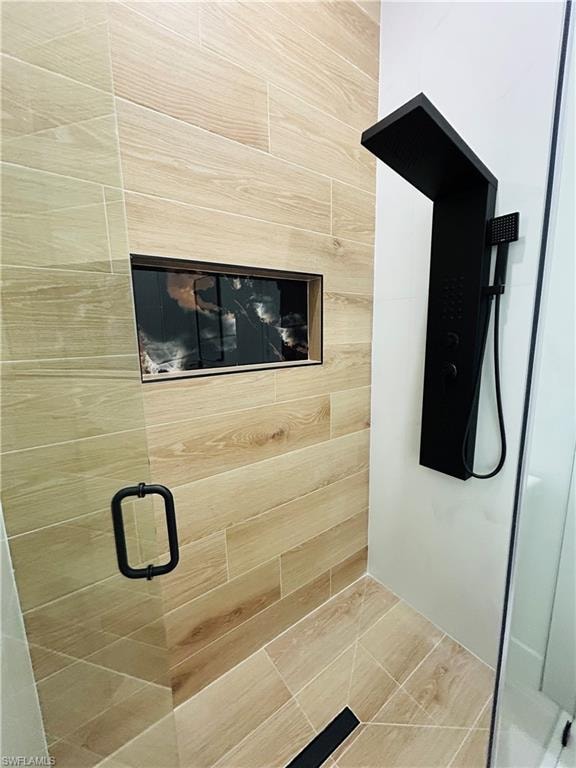 Wood-finish wall and floor tile, built-in shower niche, and a black-finish shower system