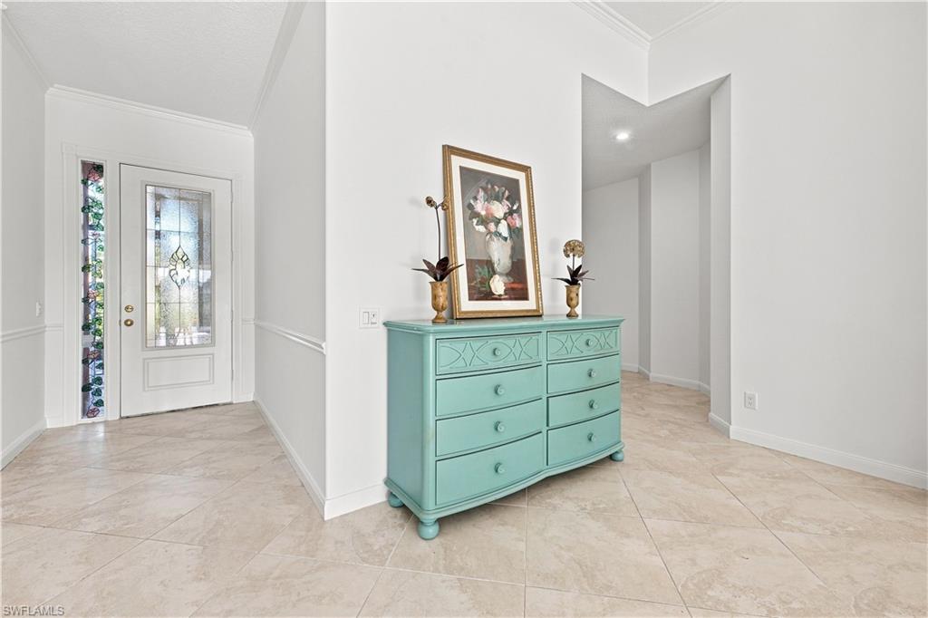 Recessed lighting, tile flooring, crown molding, chair rail molding, and a decorative glass entry door with a sidelight