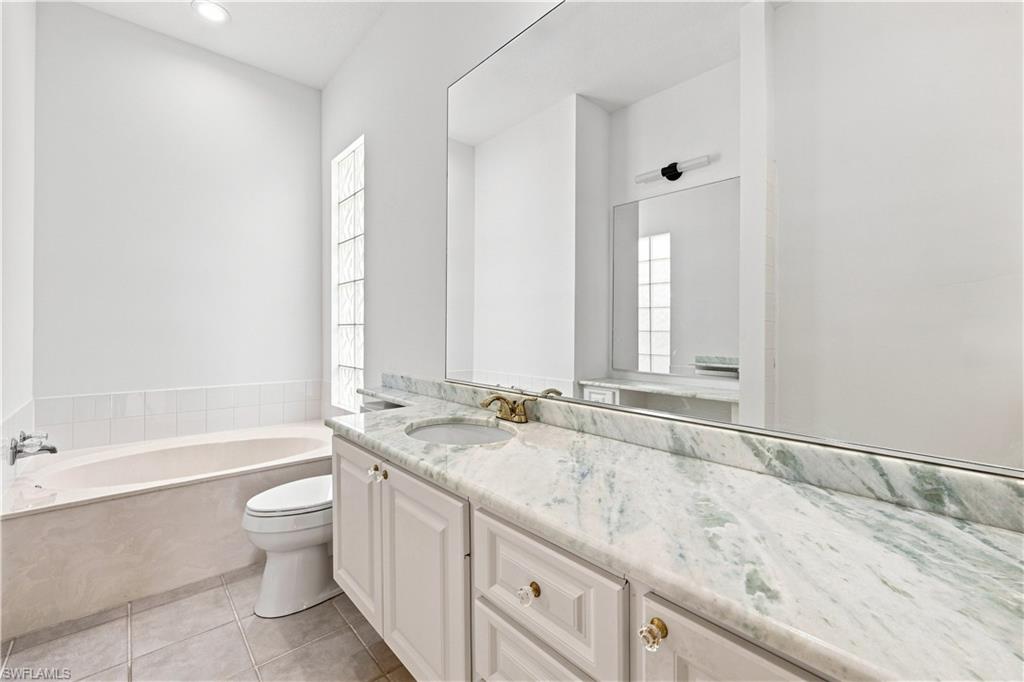 White vanity with a light-toned countertop, integrated sink, and an expansive wall-mounted mirror