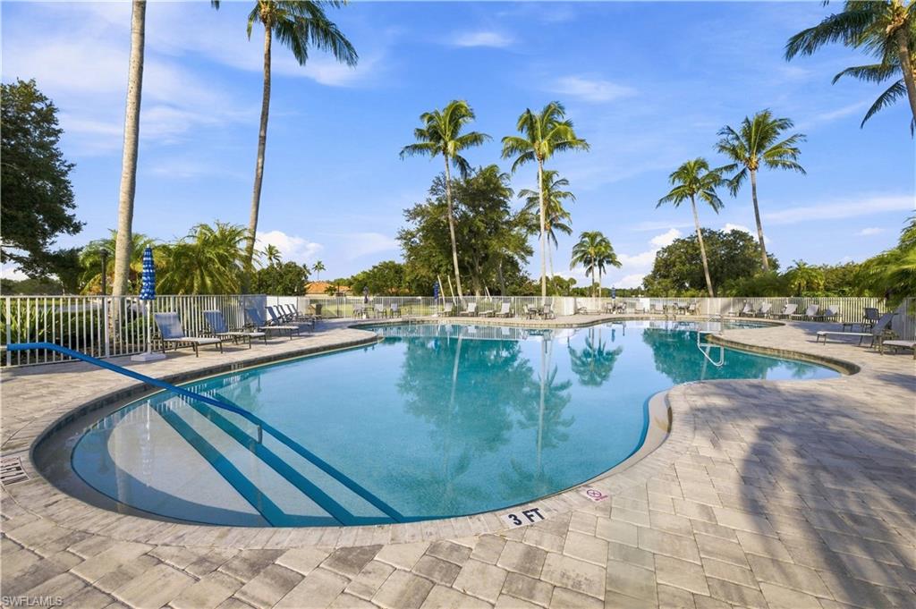 Resort-style pool with integrated steps, surrounded by a paver deck, and bordered by a white picket fence