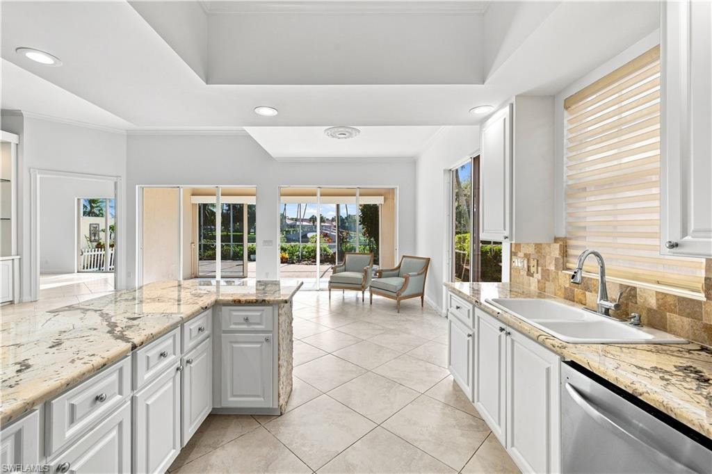 Kitchen featuring white cabinetry, light-toned countertops, a stainless steel sink, and tile flooring