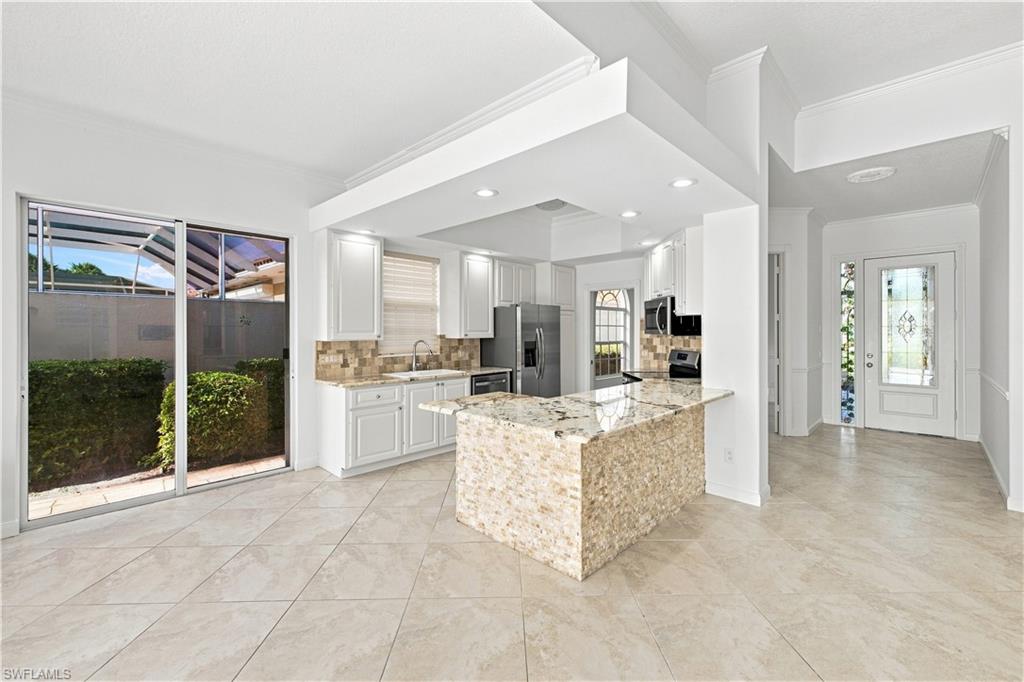 Gourmet kitchen with white cabinetry, stainless steel appliances, granite countertops, and a stone-clad island