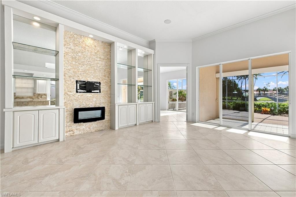 Built-in cabinetry with glass shelving, stacked stone accent wall, recessed electric fireplace, large format tile flooring, and sliding glass patio doors