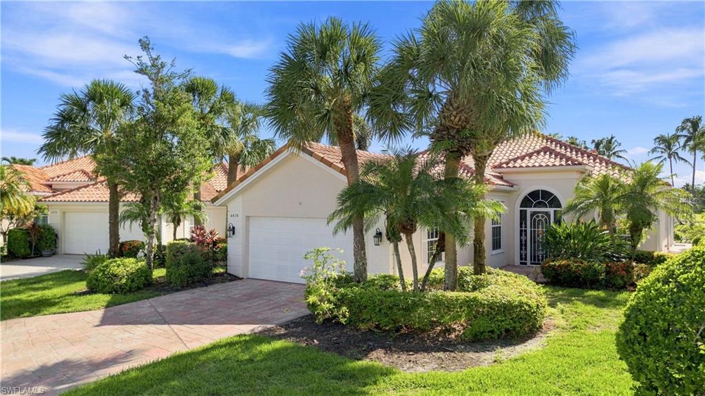 Mediterranean-style residence featuring a tile roof, arched entryway with decorative ironwork, attached garage, and mature palm trees