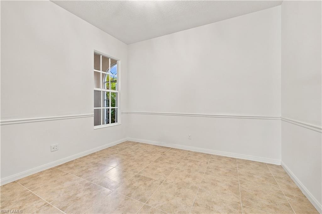 Room with tile flooring, white walls, and chair rail molding
