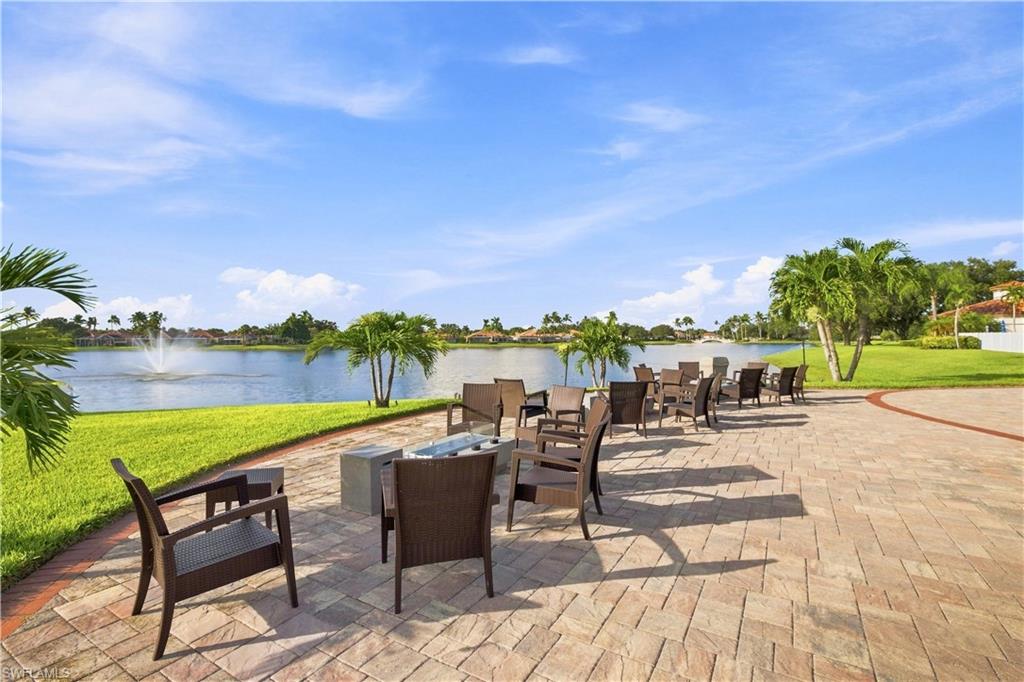 Expansive paver patio with a water feature, lush lawn, and mature palm trees