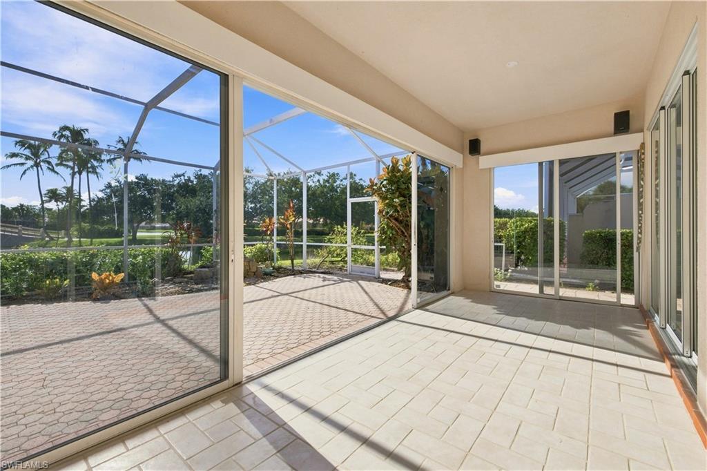 Screened patio with large format tile flooring, multiple sliding glass door entries, and paver patio beyond