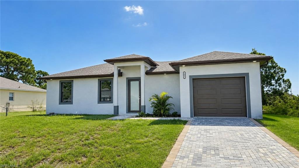 Stucco exterior with hip roof, paver driveway, and an integrated garage