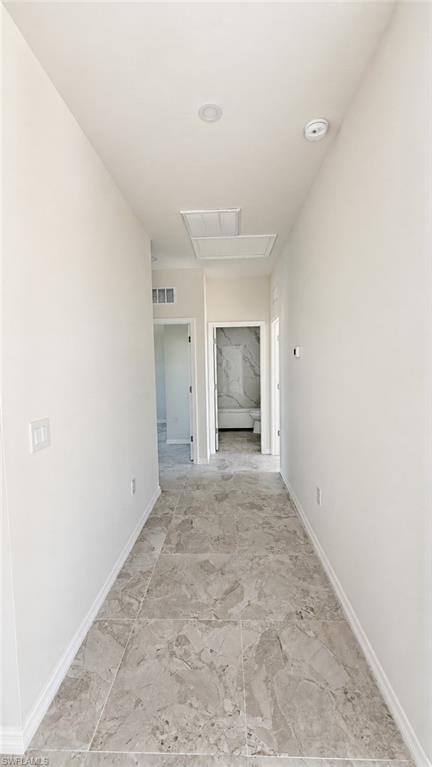 Hallway featuring large format stone-finish tile flooring, recessed ceiling lighting, and white baseboards