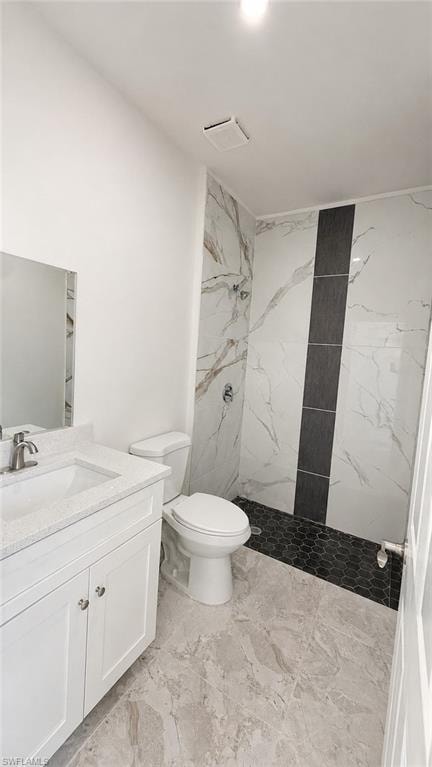 White vanity with a light-toned countertop, shower with marble-patterned wall tile, dark accent tile, and dark hexagonal floor tile