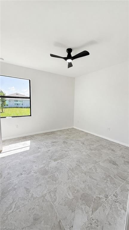 Black ceiling fan with integrated lighting, large format gray tile flooring, white walls, and a black-framed window